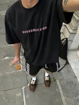 Remera oversize gris con efecto acid wash y estampa frontal con la leyenda "WORLDWIDE TOUR" en tipografía gótica.
