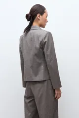 Blazer de corte sastre con doble botonadura frontal, solapas clásicas y estructura entallada, confeccionado en tejido de color beige melange.