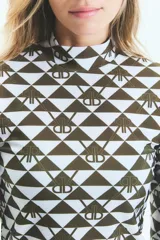 Polera de manga larga con cuello alto, confeccionada en lycra estampada con diseño geométrico de triángulos y monograma exclusivo de la marca.