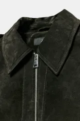 Cazadora de piel ante color verde oscuro, con cuello solapa, manga larga con trabillas en los hombros, bolsillos delanteros de plastrón con solapa y botones a presión, bajo elástico y cierre frontal con cremallera.