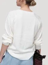 Sweater de punto color beige claro, con escote redondo y cierre frontal parcial de botones con reborde metalizado, mangas largas abullonadas y puños y ruedo elásticos.