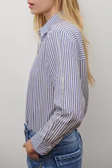 Camisa de mujer a rayas verticales blancas y rosadas, con cuello clásico, cierre de botones frontal y mangas largas con puños abotonados.