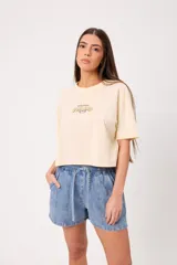Remera coral cropped, de manga corta, con estampa trasera colorida de un perro surfeando y el texto "Rusty County Surf Club".