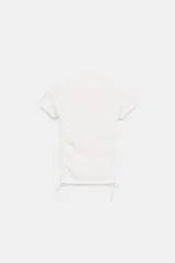 Camiseta blanca de cuello redondo y manga corta, con frunces laterales ajustables que permiten modificar el largo y el ajuste de la prenda.