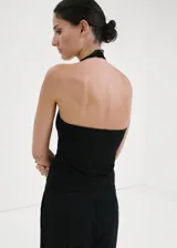 Top negro de algodón con diseño entallado, cuello halter y ribetes de encaje en los hombros y cuello. No incluye mangas.