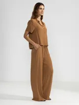 Pantalón palazzo negro de crepe con cintura elastizada, bolsillos laterales y terminaciones en cobre.