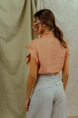 Pantalón de corte ancho y silueta abombada, color gris claro, con bolsillos frontales y costuras decorativas verticales.