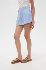 Short de calce alto y corte holgado, confeccionado en tela de viscosa color celeste, con cintura elástica fruncida.