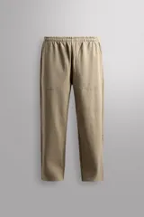Pantalón jogger de corte relajado confeccionado en tejido compacto de algodón. Presenta cintura elástica con cordón interior, bolsillos frontales en la cadera y un bolsillo trasero de plastrón.