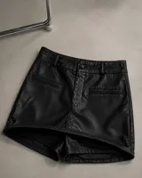 Short pollera de cuero sintético negro con diseño de tiro alto, trabillas para cinto, bolsillos delanteros simulados y cierre frontal con botón.