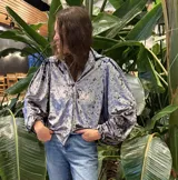 Camisa de terciopelo con efecto desgastado, de corte holgado con mangas abullonadas y puños elásticos. Presenta cuello clásico y cierre frontal con botones.