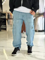 Pantalón cargo de jean azul claro, con bolsillos laterales tipo cargo en las piernas y bolsillos frontales aplicados, de corte ancho y holgado.