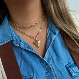Collar dorado de doble cadena con dije de diente de tiburón.