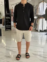 Camisola blanca de lino de manga larga con cuello mao y tira de botones frontal.