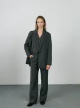 Chaleco sastrero gris con estampado a cuadros, escote en V y cierre frontal con botones.