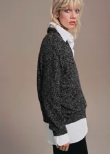 Jersey de punto jaspeado en tonos grises y negros, con cuello en V profundo, mangas largas y diseño recto holgado.