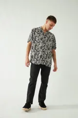 Camisa de manga corta con cuello cubano, confeccionada en viscosa con estampado de hojas en tonos azules. Presenta cierre frontal abotonado y corte slim.
