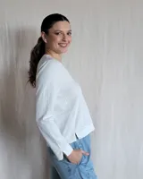 Remera de algodón color blanco, con escote en V y detalle de pespuntes decorativos en color beige. Presenta mangas largas y un corte recto con aberturas laterales en el ruedo.