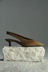 Zapatos destalonados de tacón kitten color marrón con acabado efecto ante y punta fina. Cuenta con tira elástica en el talón.