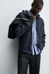 Sudadera hoodie relaxed fit color azul marino, confeccionada en tejido waffle con estructura cuadrillé. Cuenta con capucha ajustable, manga larga, bolsillos delanteros tipo canguro, acabados en rib y cierre frontal de cremallera. Presenta un efecto lavado.