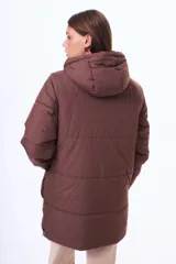 Campera acolchada de corte largo, color negro, con cierre frontal, capucha ajustable con cordones y bolsillos frontales tipo cargo.