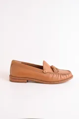 Mocasines negros de cuero con borlas y costuras decorativas.