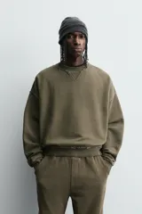 Sudadera de corte boxy fit con efecto lavado, cuello redondo con detalle de costura triangular y acabados con bordes deshilachados en el ruedo y las costuras. Presenta manga larga con puños acanalados.
