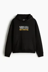 Canguro negro de mezcla de algodón con interior cepillado suave, capucha forrada y bolsillo canguro. Presenta hombros caídos y remate acanalado en puños y bajo. Estampado frontal con el logo de "Nirvana" en blanco y "Nevermind" en amarillo.