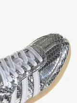 Championes Adidas Samba LT con acabado metálico plateado y textura de piel de serpiente. Presenta las icónicas tres tiras blancas en los laterales, suela de goma color caramelo y cierre de cordones.