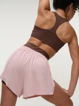 Short deportivo de color gris, confeccionado con tela dry fit, con cintura elastizada y aberturas laterales. Cuenta con calza interna negra ajustada.