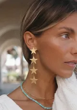 Caravanas colgantes doradas con diseño de cuatro estrellas en cascada.