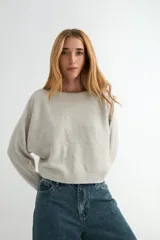 Sweater de punto en color beige, con cuello redondo, mangas largas de corte holgado y puños ajustados.