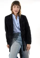 Blazer de gamuza negra con solapas clásicas, cierre frontal con botones y detalle de flecos en el ruedo. Cuenta con bolsillos laterales.