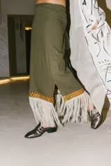 Pollera midi negra con detalle de cuero calado y flecos blancos en el ruedo.