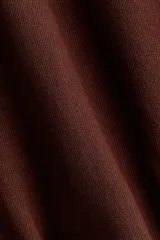 Campera oversized de sarga color marrón, con cuello, cierre frontal y bolsillos laterales ribeteados. Cuenta con mangas abullonadas, puños elásticos y bajo globo para una silueta redondeada.