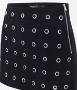 Short pollera corto de bengalina, con diseño ajustado y detalle de ojalillos metálicos distribuidos por toda la prenda. Cuenta con cierre lateral invisible.