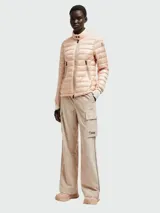 Chaqueta acolchada color rosa pálido con cierre frontal de cremallera, cuello alto y bolsillos laterales con cremallera.