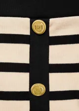 Falda corta de tejido de punto con diseño evasé, estructura de rayas horizontales en beige y negro, cierre frontal con botones decorativos y dos bolsillos de solapa con botón.