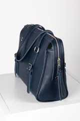 Cartera tipo bolso de mano y hombro de cuero color bordó, con diseño estructurado, doble asa corta y detalles de correas con hebillas metálicas en el frente.