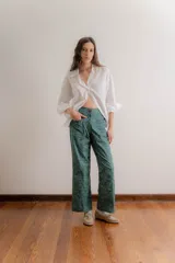 Pantalón de corte recto y tiro medio, confeccionado en gabardina estampada con un diseño botánico en tonos verdes y azules. Presenta bolsillos frontales tipo parche y cierre con botón.