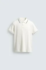 Remera polo de punto canalé color azul marino, de corte regular fit, con cuello solapa y cierre frontal de botones a presión. Cuenta con mangas cortas con ribetes blancos en los bordes del cuello y de las mangas.