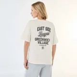 Camiseta de corte oversize color blanco crudo, con cuello redondo y mangas cortas. Presenta un pequeño estampado tipográfico en el pecho con la frase 'East Side League'.