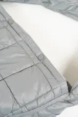 Cartera tipo hobo de diseño acolchado con costuras cuadradas, confeccionada en material sintético de acabado satinado. Cuenta con un asa única integrada y cierre mediante botones a presión en la parte superior.