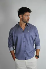 Camisa de manga larga con estampado de rayas verticales finas en tonos azul y blanco. Presenta cuello clásico, cierre frontal con botones y puños con vuelta en contraste.