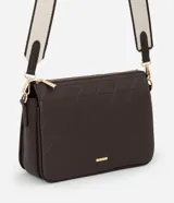 Bolso tipo bandolera de color marrón oscuro, con textura de cuero sintético (PU) y patrón geométrico acolchado en la parte frontal. Cuenta con herrajes dorados, cierre superior y una correa ancha de tela bicolor (beige y marrón) ajustable.