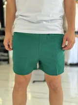 Short de baño gris liso, con diseño clásico y un pequeño parche circular con logo en la parte inferior de la pierna izquierda.
