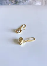 Aros colgantes dorados con forma de concha marina, con circonitas y perla de río lila.