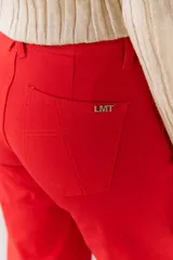 Pantalón color beige de corte recto, confeccionado en algodón y spandex. Presenta tiro medio y cierre frontal con botón y cremallera. Incluye cinturón marrón con hebilla plateada.