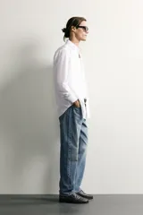 Jeans regular fit confeccionados en denim de algodón celeste con efecto lavado, de cinco bolsillos y cierre frontal con cremallera y botón.