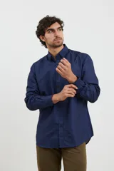 Camisa de manga larga en color azul oscuro con estampado de micro puntos claros. Presenta cuello con botones, cierre frontal abotonado y puños ajustables.